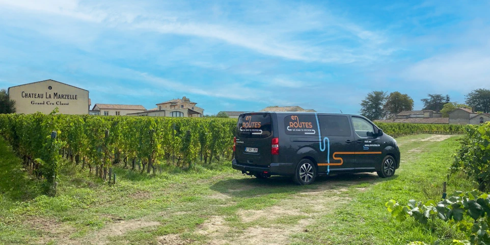 Luxe minibus Peugeot Traveller huurwagen op reis door wijnvelden met bestickering van En Routes erop